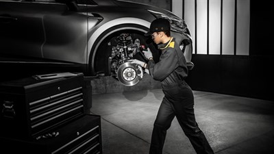 A technician repairing the bottom of a car lifted from a hydraulic lift